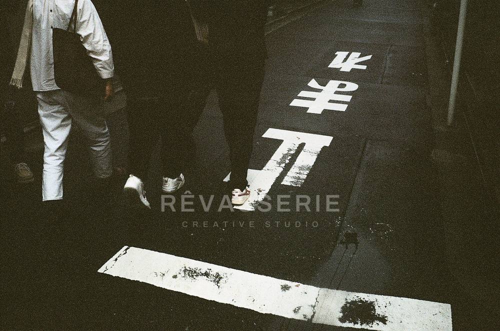 feet crossing a tokyo street with tomare stop marking, black and white 35mm film